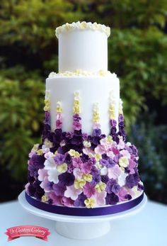 a three tiered cake with purple and white flowers