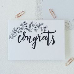 congratulations card surrounded by paper clips and crochet doily on a white surface