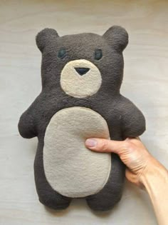 a hand is holding a stuffed teddy bear