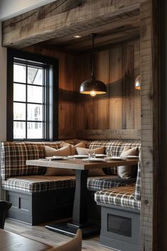 an empty restaurant with wooden walls and plaid cushions on the tables, along with black framed windows