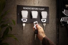 a person is holding keys in front of a sign that says remove before flight