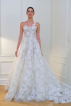 a woman in a white wedding dress standing on a wooden floor