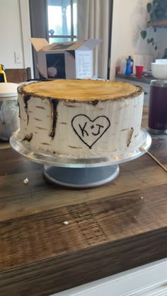 a cake that has been decorated with a heart and initials on the side is sitting on a wooden table