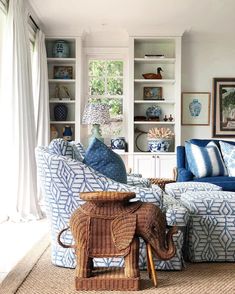 a living room filled with blue and white couches next to a wooden elephant figurine