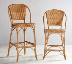 two wicker bar stools sitting next to each other in front of a white wall