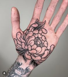 a person's hand with a flower tattoo on it and the palm of their hand