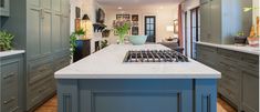 a kitchen with blue cabinets and white marble counter tops, along with an island in the middle