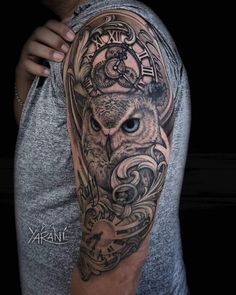 a man's arm with an owl and clock tattoo design on it, in black and grey