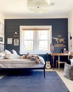 a bedroom with a bed, desk and two windows in the room that is painted blue