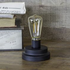 a light bulb sitting on top of a wooden table next to books and a stack of papers