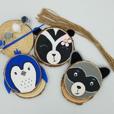 three wood slices with painted animals on them next to some yarn and scissors in the background