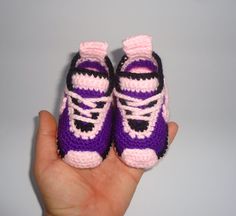 a hand holding a small crocheted purple and black sneaker shoe ornament