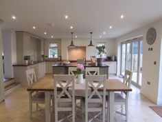 a dining room table with chairs and a clock on the wall in front of it