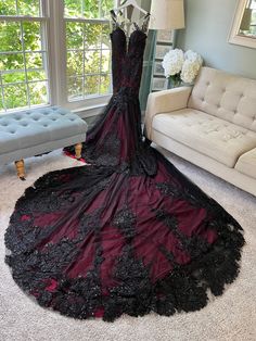 a black and red dress on display in front of a couch with a white chair