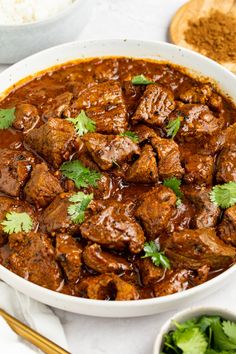 a white bowl filled with meat and garnished with cilantro