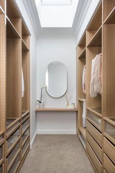 an empty walk - in closet with lots of wooden shelves and mirrors on the wall