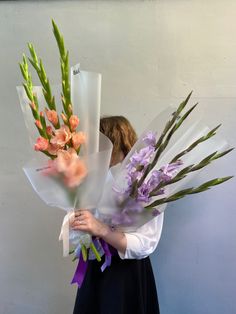 a woman holding flowers in her hands and wearing a white shirt with purple ribbon around the neck