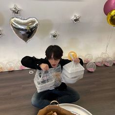 a person sitting on the floor with some balloons and bags in front of them,