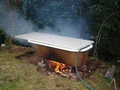 an old bathtub sitting on top of a pile of rocks next to a fire