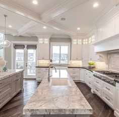 a large kitchen with white cabinets and marble counter tops, along with an island in the middle