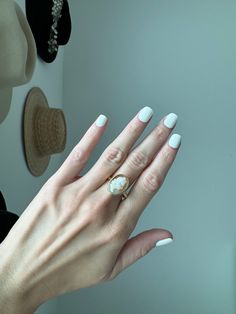 a woman's hand with white manicured nails and a ring on her finger