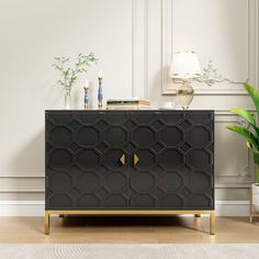 a black and gold cabinet in a white room with potted plants on the side