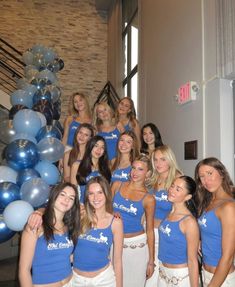 a group of young women standing next to each other in front of blue and silver balloons