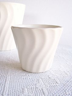 two white vases sitting on top of a table