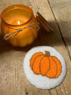 a candle sits next to a coaster with a pumpkin on it