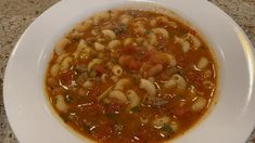 a white bowl filled with pasta and meat soup