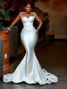 a woman standing in front of a couch wearing a white dress with beading on it