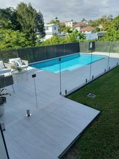 a backyard with a swimming pool surrounded by grass and fenced in area next to it