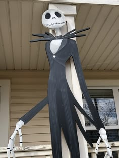 a halloween decoration with a skeleton on it's head and arms, standing in front of a house