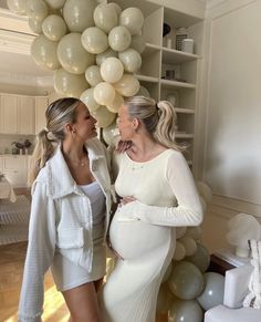 two women standing next to each other in front of balloons