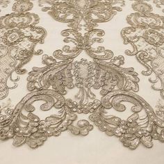 an embroidered fabric with silver thread and sequins on white background, closeup