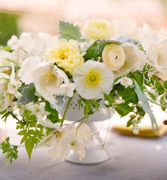 a white vase filled with lots of flowers on top of a table next to a yellow plate