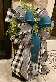 a blue and white bow with greenery in it on top of a black stand