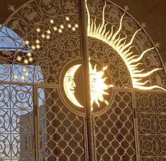 the sun and moon are lit up in front of an iron gate with intricate designs