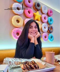 a woman sitting at a table with donuts in front of her and a star on the wall behind her