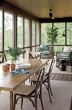 a wooden table sitting on top of a patio next to a tall window filled with lots of windows