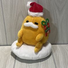 a yellow stuffed animal with a santa hat on it's head sitting on a cloud