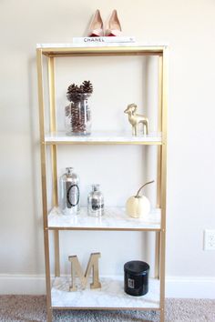 a shelf with various items on it and the letter m in gold painted letters below