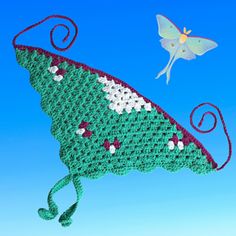 a crocheted bag with a butterfly flying over it and another object in the sky