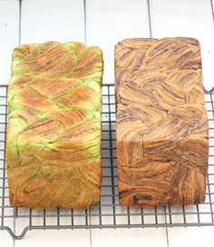 there are two different types of bread on the cooling rack, one is brown and one is green