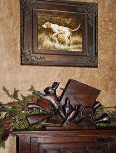 a painting hanging on the wall next to a wooden cabinet with birds and dog figurines