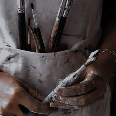 a person with dirty hands holding some paint and brushes in their pockets while wearing gloves