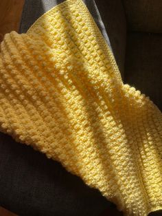 a yellow crocheted blanket laying on top of a couch