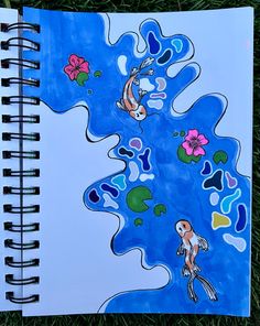 a notebook with an image of two fish and flowers on the cover, sitting in grass