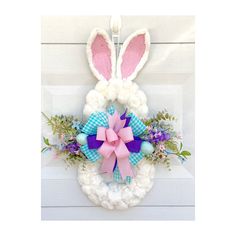 a wreath with bunny ears and flowers on it is hung on the front door for easter