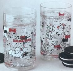 two glasses with cartoon characters on them next to oreo cookies and one glass has an ice cream sandwich in it